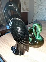 Side angle of the heron vase showing its detailed sculpted wings and head in dark glossy glaze.