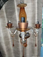 Photo of vintage chandelier showing three amber glass arms with metal candle holders and amber glass teardrop pendants; central amber glass column and ceiling mount also visible.
