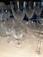 Photo showing tall wine glasses, smaller stem glasses, and liqueur glasses with starburst and diamond cut pattern in clear crystal.