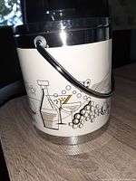 Front view of the biscuit barrel with handle and cocktail-themed illustrations