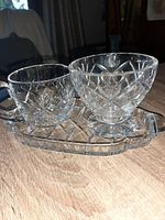 Photo showing a set of a crystal creamer, a sugar bowl, and a cut crystal tray on wooden surface with natural lighting.