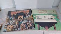 Two Frank Zappa album covers, "200 Motels" double album showing colorful illustrated cover with characters and Frank Zappa, and "Waka/Jawaka" with green cover and cartoon faucets labeled Hot and Rats.