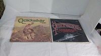 Two vinyl albums by Quicksilver Messenger Service, one showing a cowboy on horseback cover and the other a dark cover with red lettering.