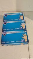 Three blue boxes of Sani Guard brand vinyl gloves, each box contains 100 small (S/P) sized gloves.