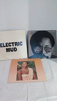 Three vinyl records displayed: Muddy Waters 'Electric Mud', Billy Cobham with portrait in sunglasses, Whitney Houston self-titled album.