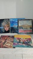 Photo shows all five vinyl record albums with covers visible: one sealed album, Bonnie Tyler, The Very Best of The Lovin' Spoonful, and two other albums.