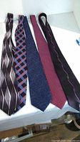Five men's ties laid out flat showing various patterns and colors.