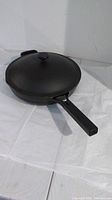 12-inch black Always ceramic skillet with lid, shown closed on white surface.