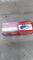 Box of ProTrek Deluxe Foot Pump showing product name, features including 0-100 PSI gauge