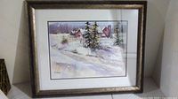 Framed winter scenery print showing snow-covered trees and houses