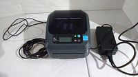 Front view of Zebra GX420d with power and data cords connected, showing overall condition and size.