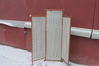Room divider showing all three fabric-covered wooden panels from front side outdoors on a concrete surface