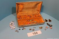 Wide shot of jewelry box with assorted rings inside and earrings arranged around it, showing various styles and colors.