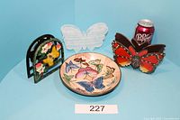 Photo of 7-inch ceramic butterfly bowl with three butterfly-themed napkin holders and a can of Dr Pepper for size reference.
