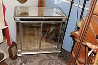 Front view of the fully mirrored cabinet showing closed doors, metal frame, and mirrored glass panels on the doors and top.