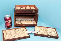 Full view of the wooden Mahjong chest holding the Mahjong tile trays beside a soda can for size comparison.