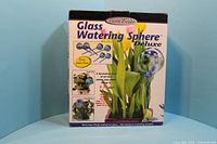 Box front showing the Handy Treats Glass Watering Sphere Deluxe 6-piece set with illustrations and product details