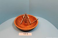 Top and angled side views of the medium brown wooden bowl with six metal nutcracker tools arranged upright inside.