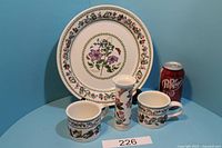 Photo showing the full set against a blue backdrop with a Dr. Pepper can for scale, includes large plate, two cups, and a vase.