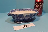 Blue and white ceramic rectangular vintage planter with ornate side handles, placed beside a Dr Pepper can for size comparison.