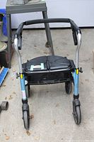 Front view of Xpresso walker showing the padded front handle bar, foldable seat, storage basket, and front wheels.