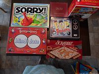 Photo showing Sorry!, Battle of the Sexes, Pop Smarts, and Scrabble games on a table.