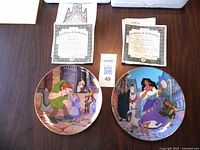 Two Bradford Exchange Disney Hunchback of Notre Dame plates on a table with certificates of authenticity