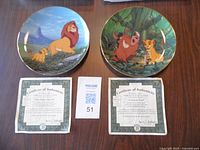 Two collectible plates from The Lion King series with certificates of authenticity.