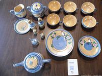 Image of the entire 33 piece vintage lusterware tea set and dinnerware including cups, plates, creamer, condiments, and teapot, arranged on a table.