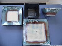 Top view of three square plates in different sizes and a matching bowl showing glaze and pattern details.