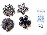 Top view of four antique brooches including floral and leaf designs with clear and black stones.