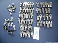 Photo showing multiple battery lugs and bolts arranged on a surface. Includes ring terminals, side post bolts, and other miscellaneous battery connection hardware.