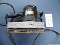 Front and top view of the Craftsman 4-inch commercial belt sander showing black handle, metal sanding base and ventilation holes.