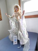 Full view of the Arianna Princess of the Sea porcelain doll standing, showing its sea-themed gown and sculpted seashell base.