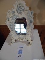 Front view of ornate Incolay stone vanity mirror showing carved cherubs and floral details