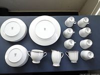 Overhead photo showing bottom view of 7 dinner plates, 6 salad plates, 8 bread/dessert plates, 8 tea cups, creamer, and sugar bowl