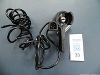 Black WARN wire winch remote control switch with protective cap over toggle switch and attached 5-pin connector plug with coiled 12' cord.