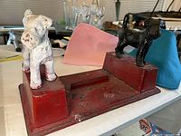 View of the boot scraper showing the two terrier dog figures on each side, one white and one black, attached to a red base.