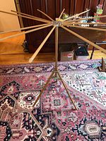 Wide view of wooden folding clothes dryer fully extended on the floor, showing tripod base, wooden rods, and surrounding environment.