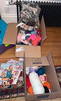 Top view of two open boxes showing yarn skeins in various colors and knitting magazines on the side