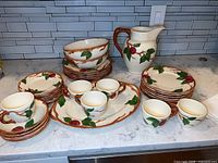 Overview of the full set including plates, cups with saucers, serving bowls, and jug arranged on a countertop.