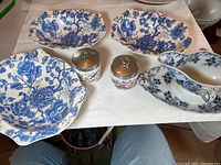 Set of three Johnson and Bros. blue and white floral serving bowls, two Aynsley jars with metal lids and floral motifs, and one Villeroy and Boch gravy dish with blue floral pattern.