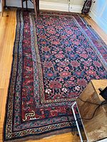 Overall view of rectangular red field Oriental style rug laid on hardwood floor