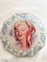 Full view of the octagonal porcelain wall plaque featuring Marilyn Monroe in a smiling portrait and full-length figure in a red dress.