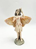 Front view of ceramic fairy figurine showing facial expression, wings, and petal-style dress with textured base.