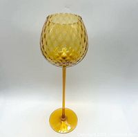 Full view of amber art glass goblet with optic pattern bowl, tall stem, and round base.