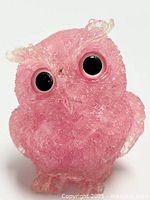 Close up front view of pink resin owl figurine with embedded amethyst crystal shards and large black eyes with pink rims.