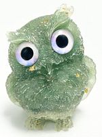 View of the owl figurine front showing textured green resin with amethyst crystal shards and large iridescent eyes