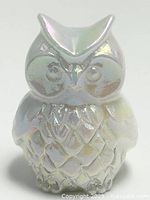 Front view of a small white jade owl figurine with iridescent sheen showing detailed carved feathers and face.