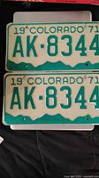Two 1971 Colorado license plates AK-8344 on a dark cloth surface, showing the full front of both plates.
